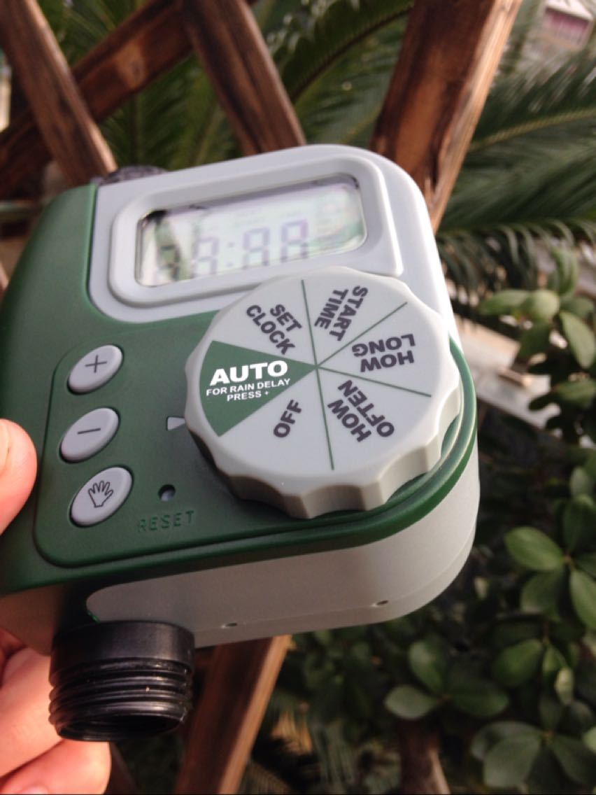 Digital garden water timer installed on a garden hose outdoors