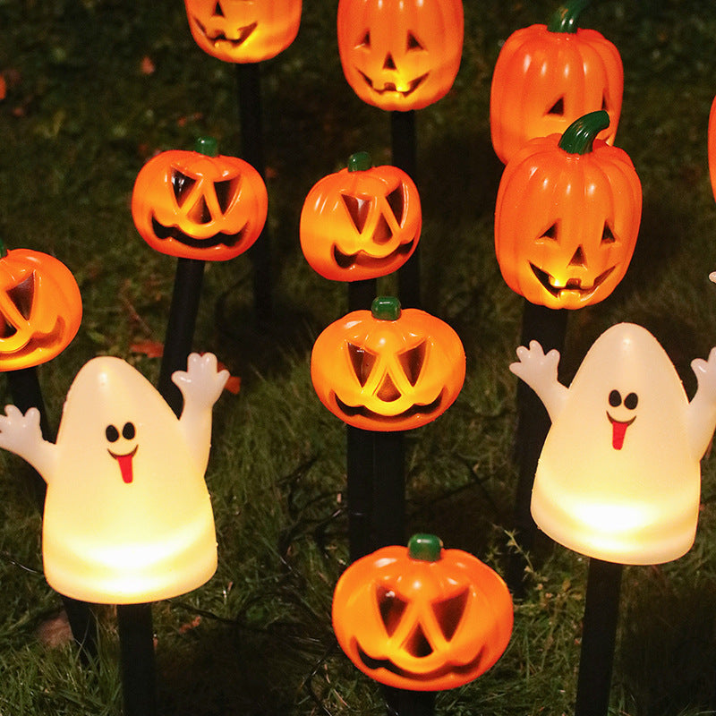 Glowing Halloween pumpkin and ghost stake lights illuminating a garden