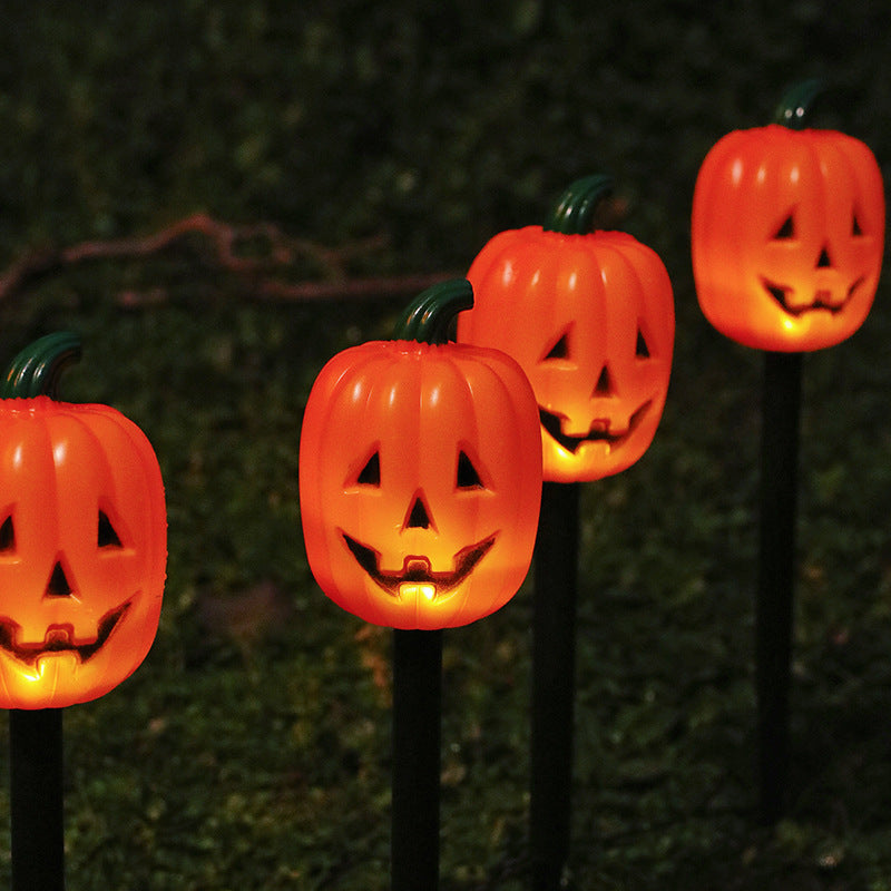 Glowing pumpkin solar stake lights decorating an outdoor garden