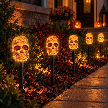 Glowing skull solar lights illuminating a landscaped garden walkway