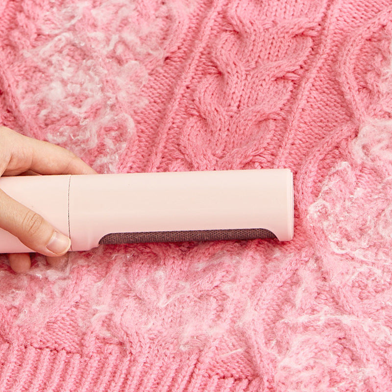 Reusable lint and pet hair remover brush used on pink fabric