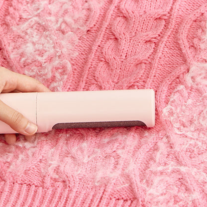 Reusable lint and pet hair remover brush used on pink fabric