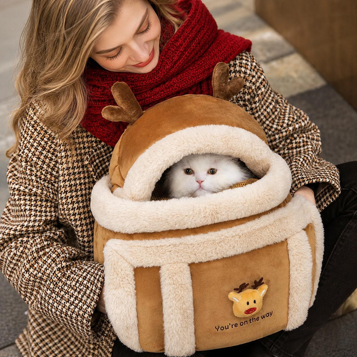 Woman carrying a reindeer-themed pet carrier with a white cat inside