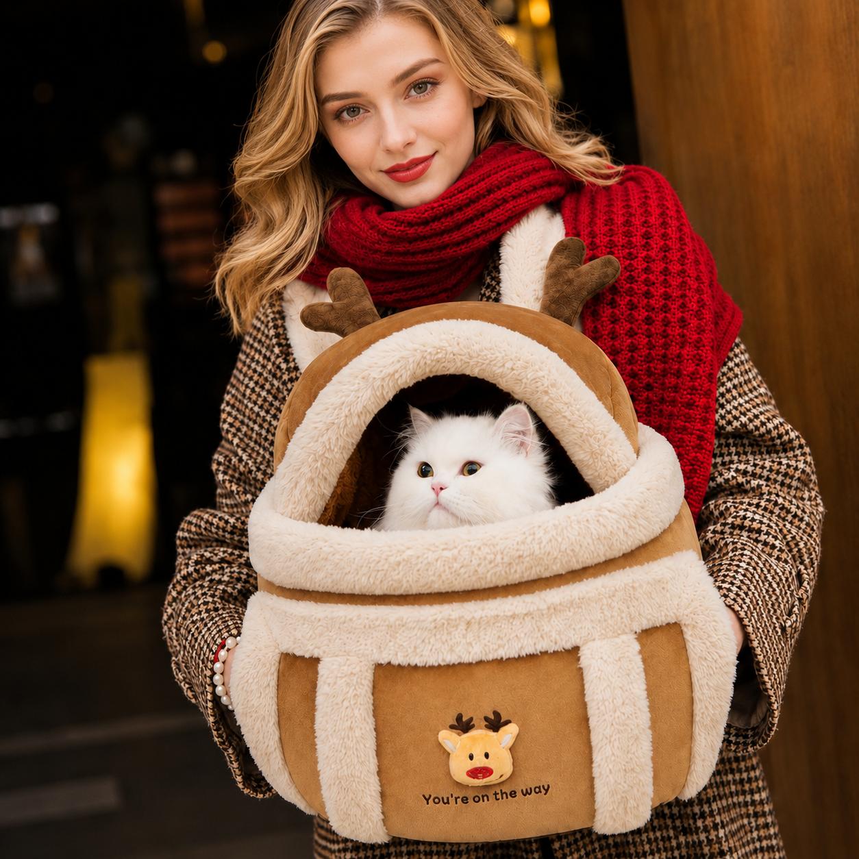 Reindeer-themed pet carrier worn by a woman with a white cat inside