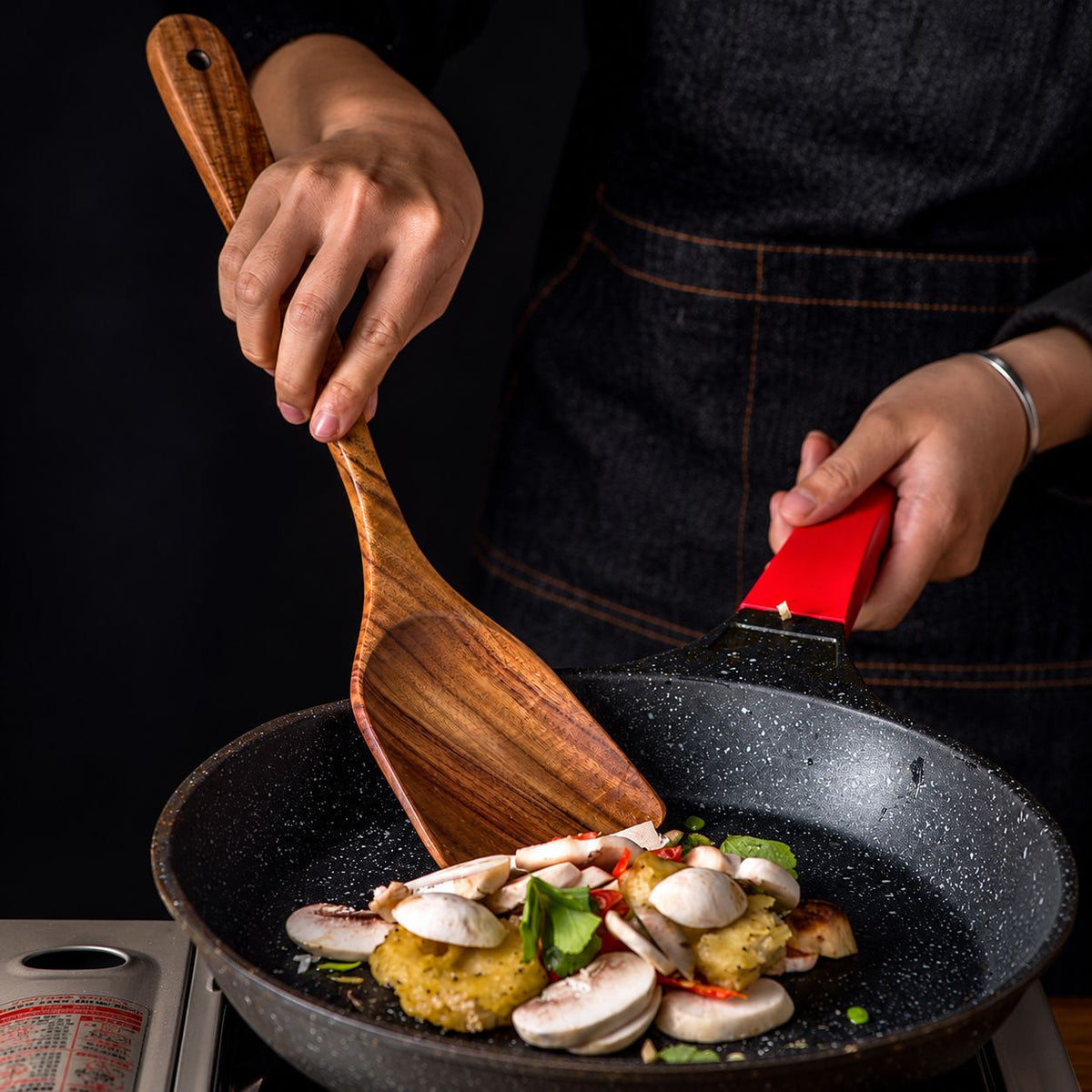 Teak wood spatula used for cooking in a pan